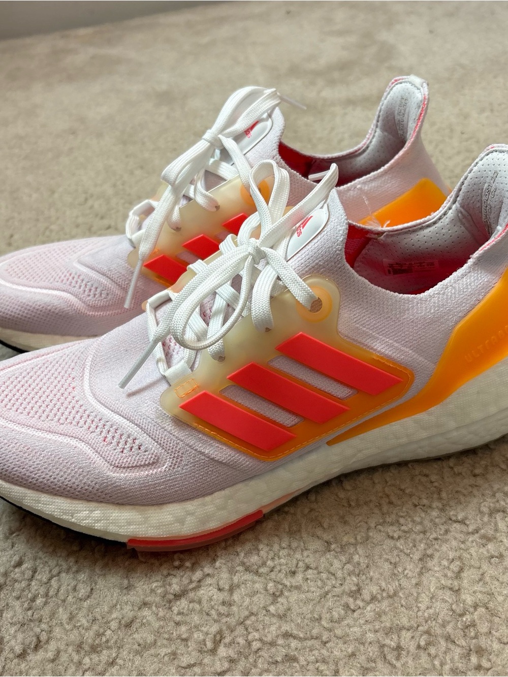 Adidas Ultraboost 22 running shoes in the White Flash Orange colorway.